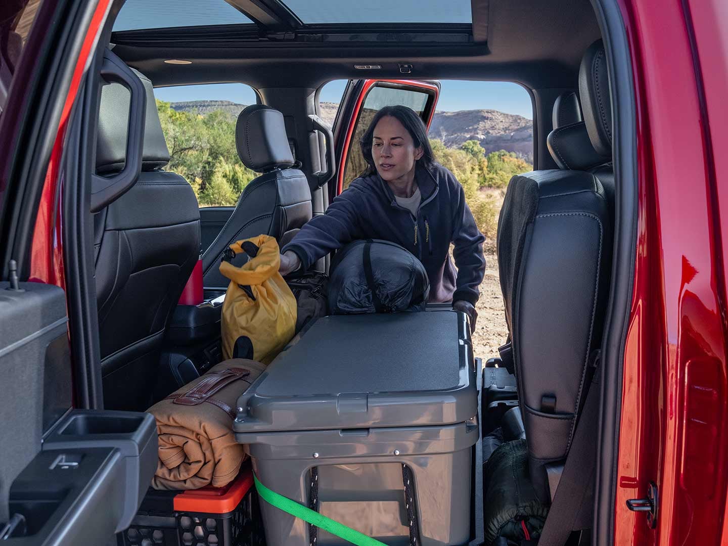 Woman loading items into the rear seating area of a 2024 F-150® truck with the seats folded up 
